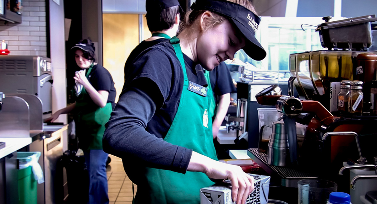student working at Starbucks making a coffee
